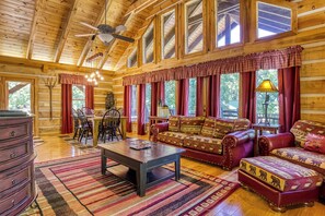 A log cabin interior with a dining area, sofa set, and a fireplace.