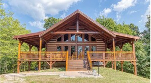 A wooden cabin with a porch, multiple windows, and a covered deck area.