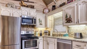 A kitchen with stainless steel appliances, wooden cabinets, and a granite countertop.