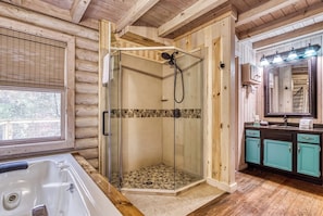 A wooden cabin interior with a glass-enclosed shower, a bathtub, and a vanity with a mirror.