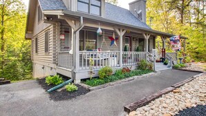 A log cabin with a porch, a satellite dish, and a flag.