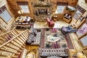 A log cabin interior with a stone fireplace, wooden walls, a dining area, and a cozy seating arrangement. - Top of the World – Scenic Log Cabin with Mountain Views, Hot Tub & Fireplaces (Sevierville)