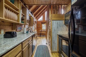 A wooden interior with a kitchen area, including a refrigerator, cabinets, and a dining table.