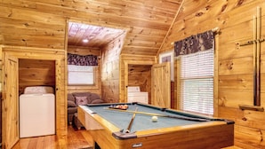 Un intérieur en bois avec une table de billard, un canapé et un lave-linge.