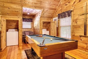 A wooden interior with a pool table, a sofa, and a washing machine.