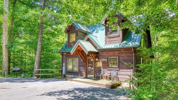Une cabane rustique dotée d’une véranda, d’une boîte aux lettres et d’un panneau indicateur.