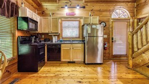 L’intérieur d’un chalet en bois comprend une cuisine équipée d’un four à micro-ondes, d’une cuisinière, d’un lave-vaisselle et d’un réfrigérateur.
