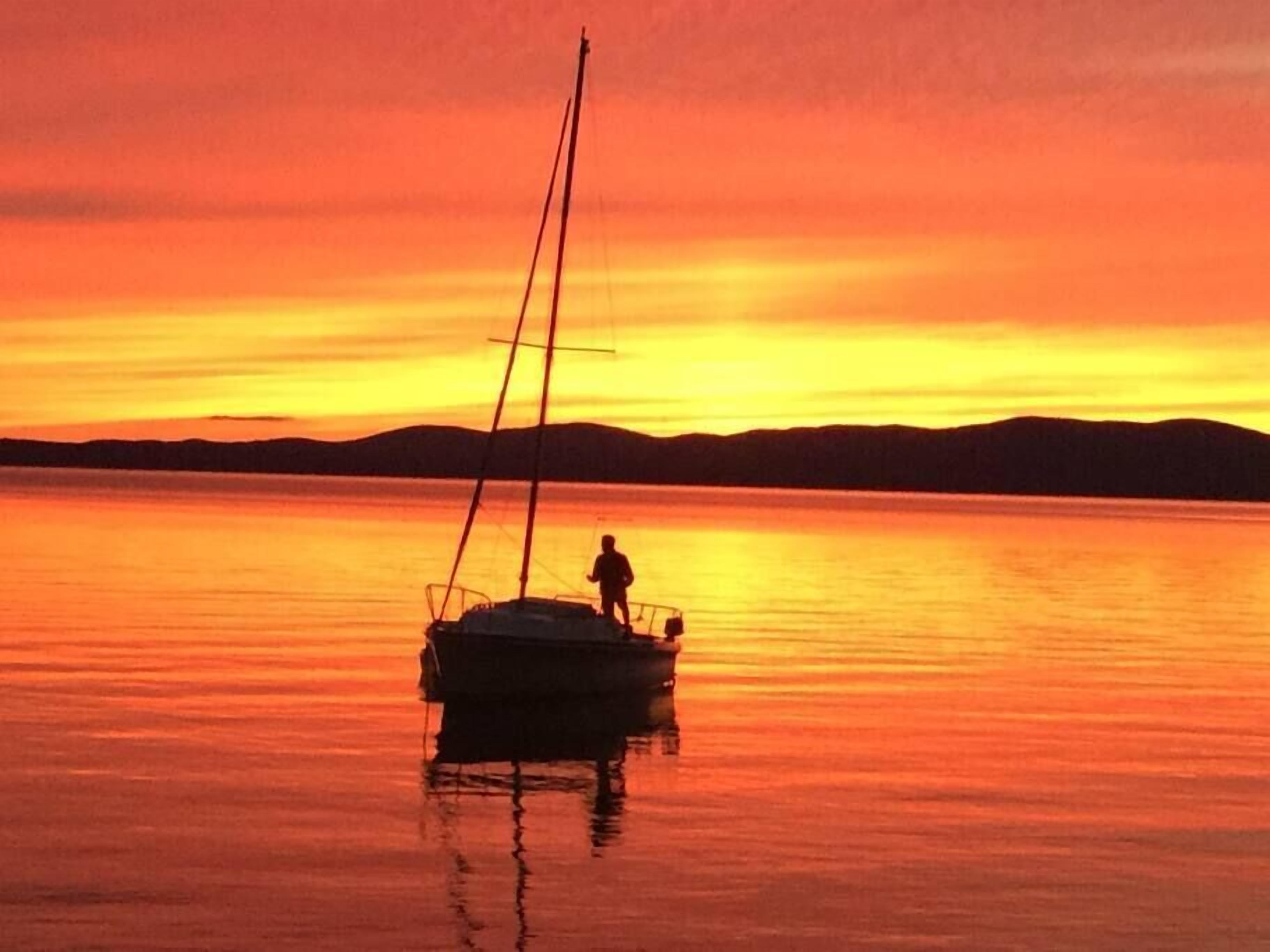 Un velero fondeado en aguas tranquilas durante el atardecer.