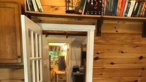 Een gezellige kamer met een geruite bank, een houten wand en een boekenkast vol boeken.