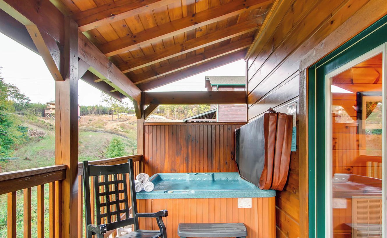 En træterrasse med jacuzzi, gyngestol og bænk.
