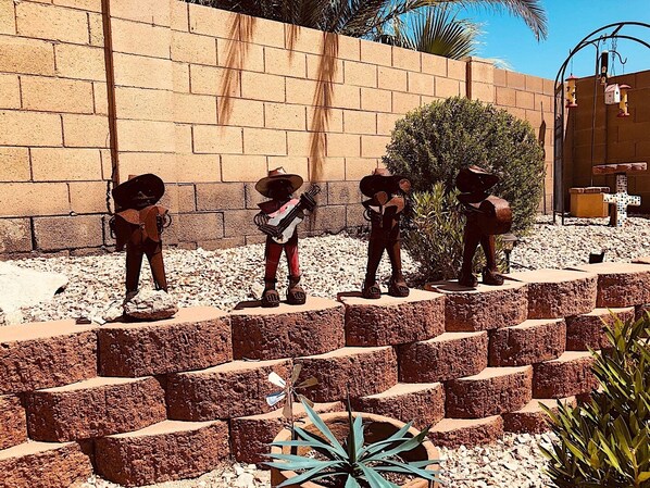 Un patio con muro de ladrillo, una palmera y una jardinera con forma de cruz.