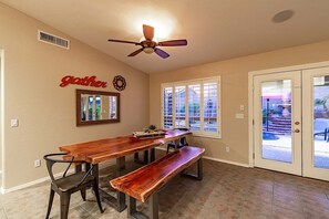 Un espace repas avec une longue table en bois, des bancs et un ventilateur de plafond.