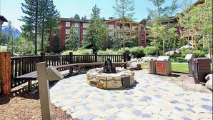 A courtyard with stone flooring, a wooden bench, a fire pit, and a wooden fence.