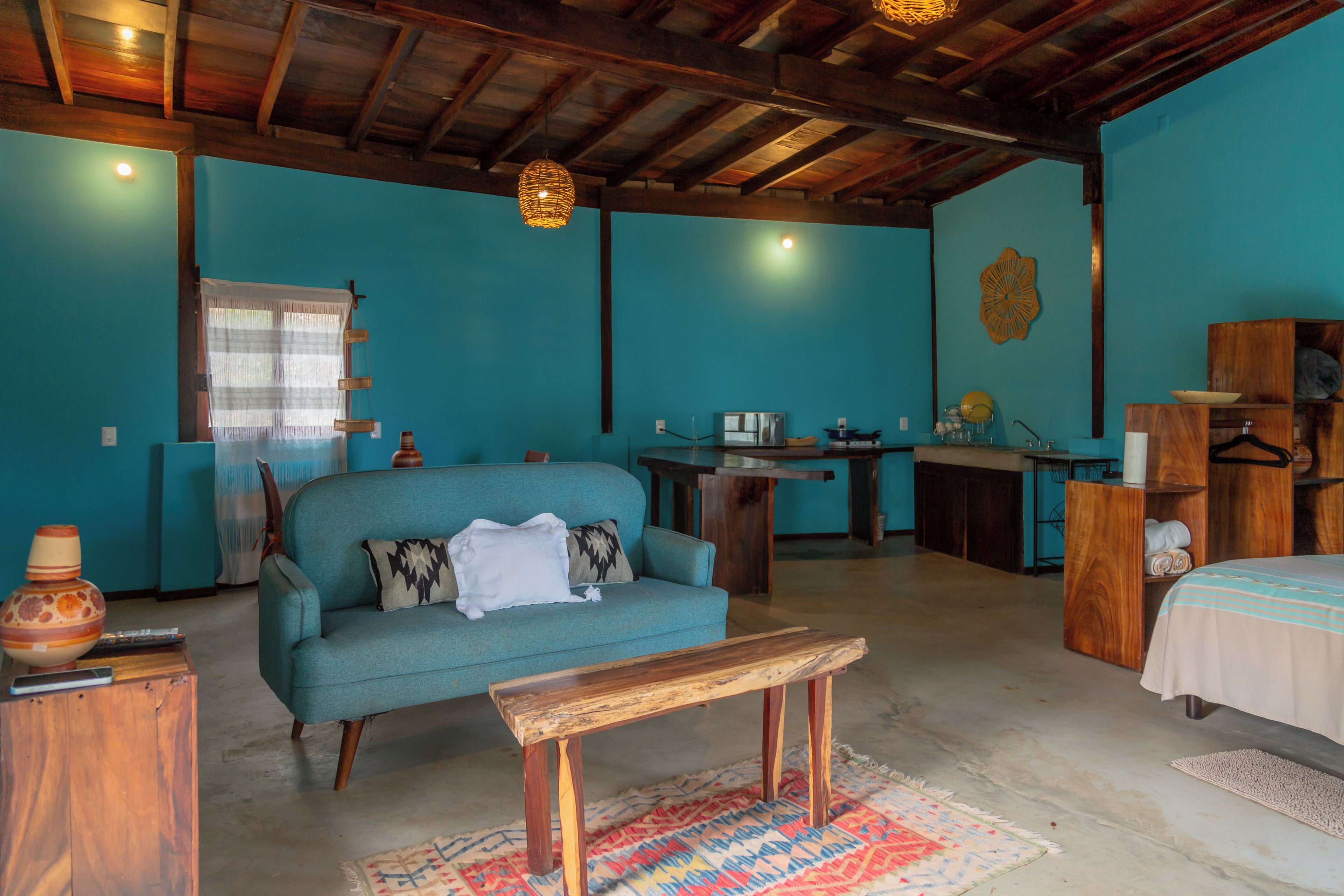 Una habitación con un sofá, una mesita de madera, un escritorio y una cama.