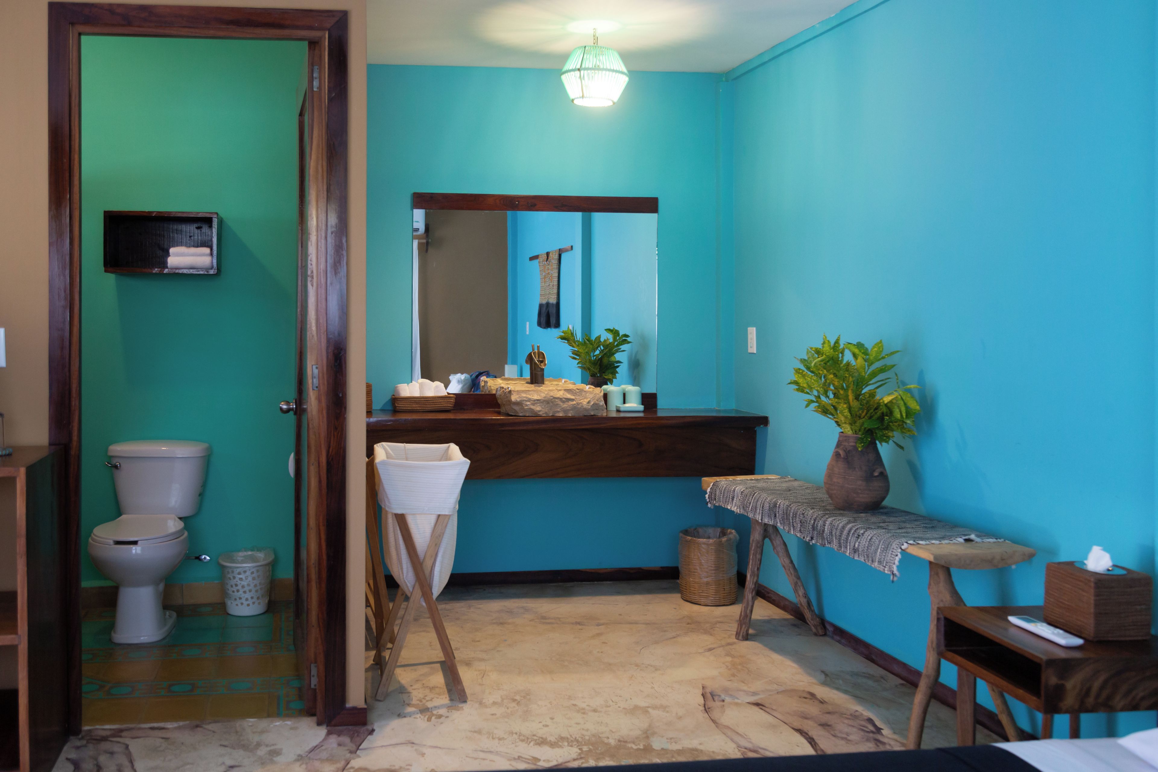 A bathroom with a toilet, sink, mirror, and a potted plant.