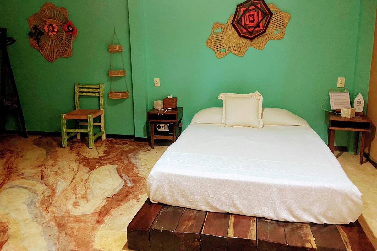 Una stanza con un letto, una sedia, un tavolino e decorazioni a parete.