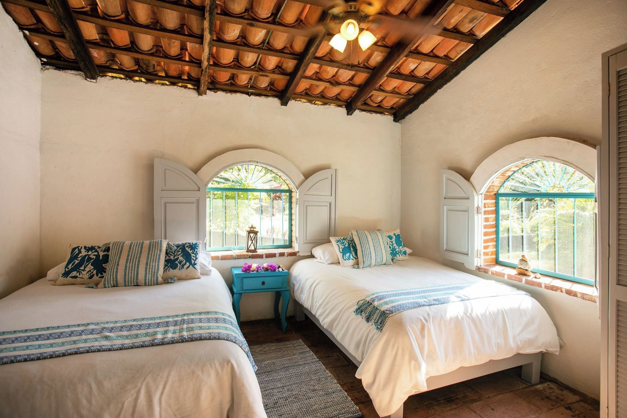 A room with two beds, a small table, and a ceiling fan.