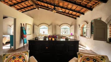 A room with a wooden ceiling, a central island with a vase and candles, and a view through arched windows.