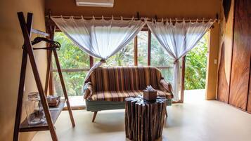 A room with a striped sofa, a small wooden table, and a large window with curtains.