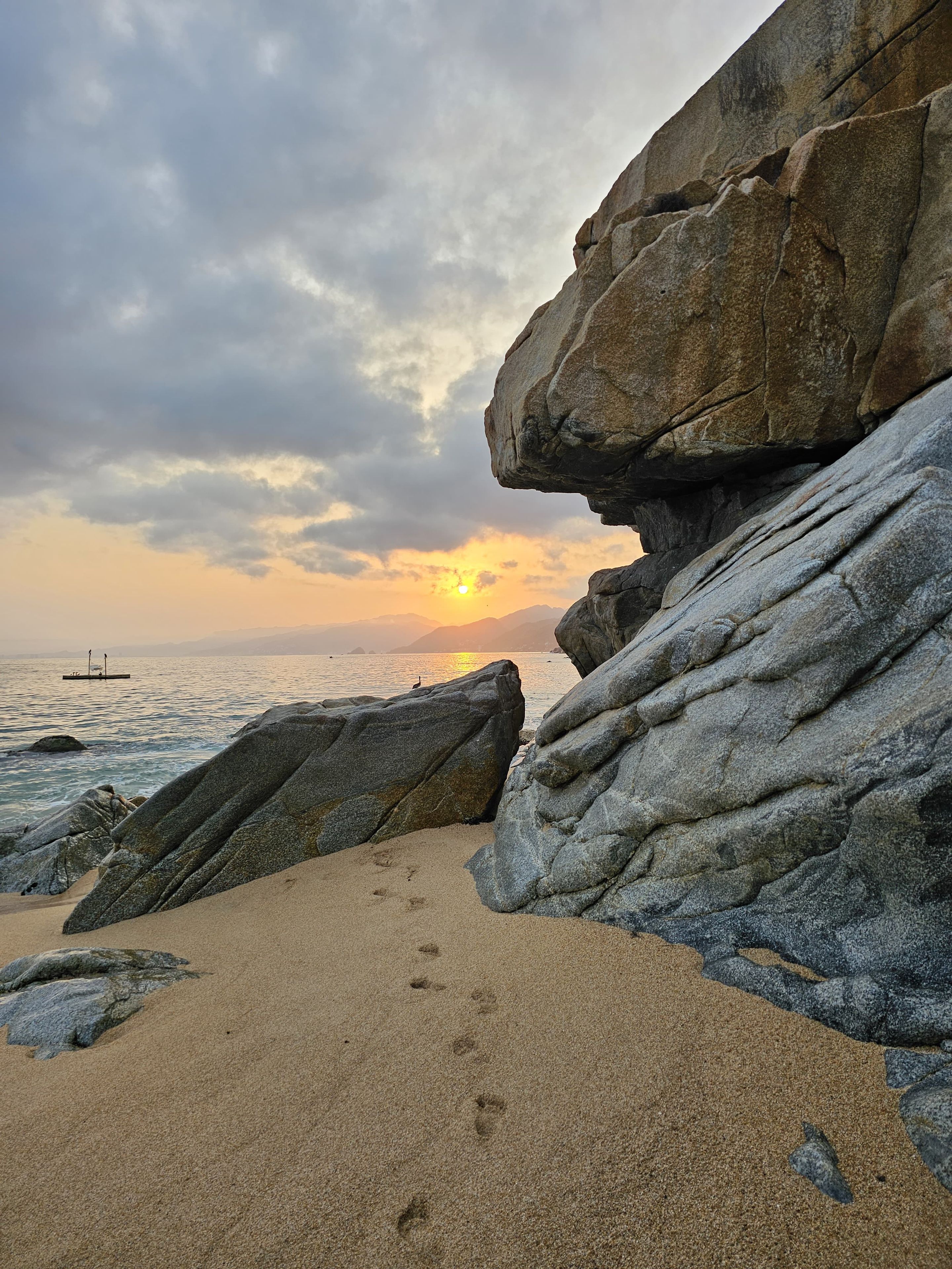 A rocky shoreline with a sunset in the background.