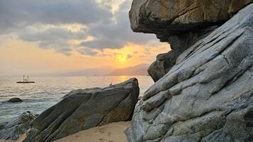 A rocky shoreline with a sunset in the background.
