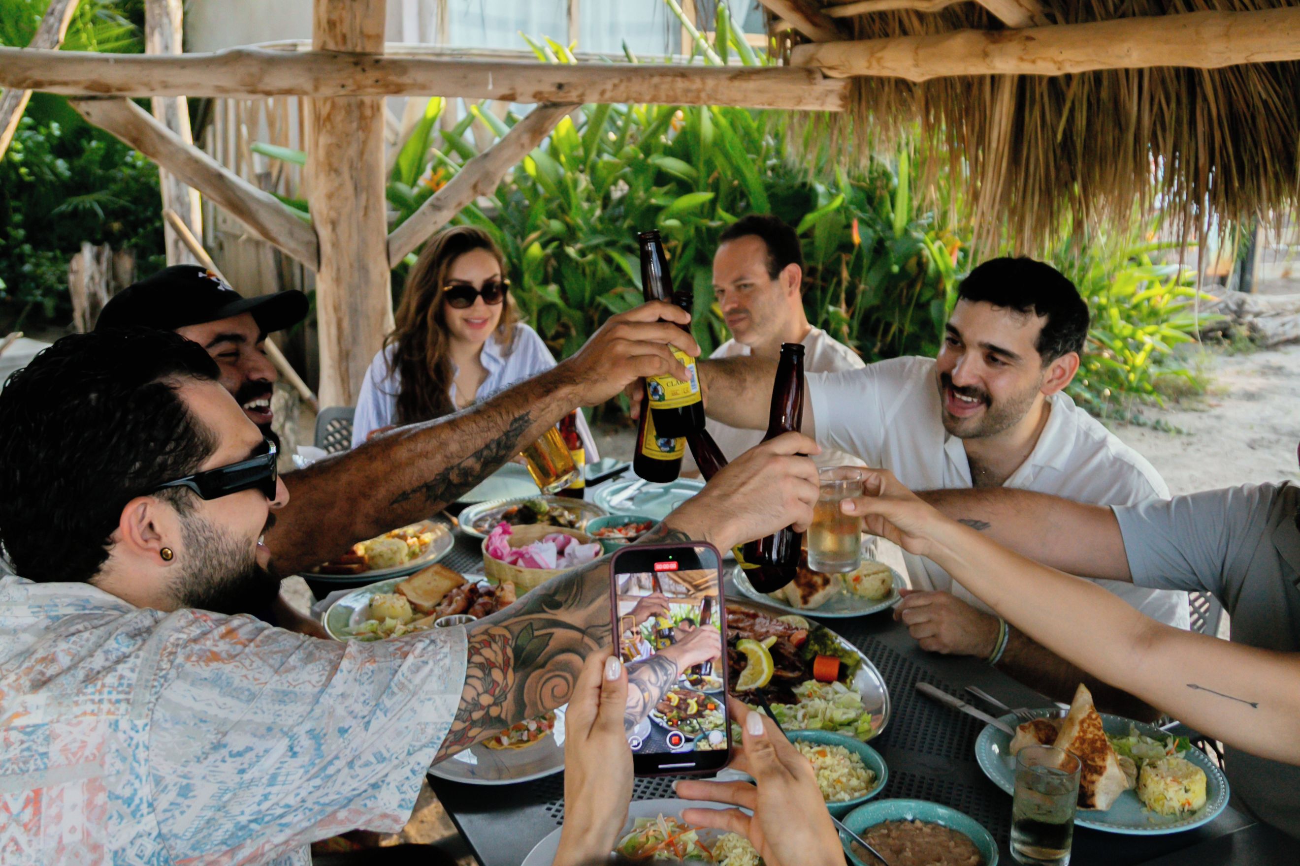 A group of people toasting with drinks at a table with various dishes.