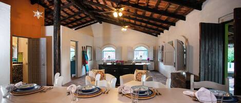 Un comedor con techo alto, vigas de madera y una isla central con asientos.