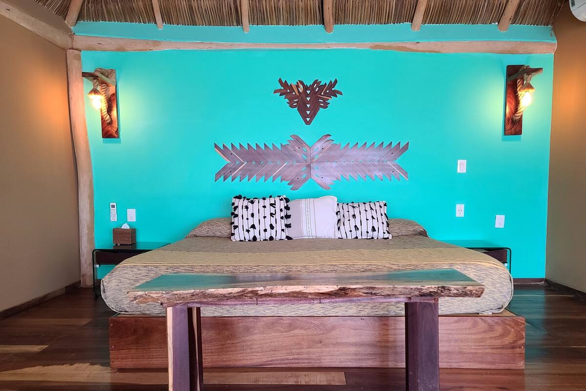 Una stanza con un letto, pavimento in legno e parete verde acqua con decorazioni a foglia.