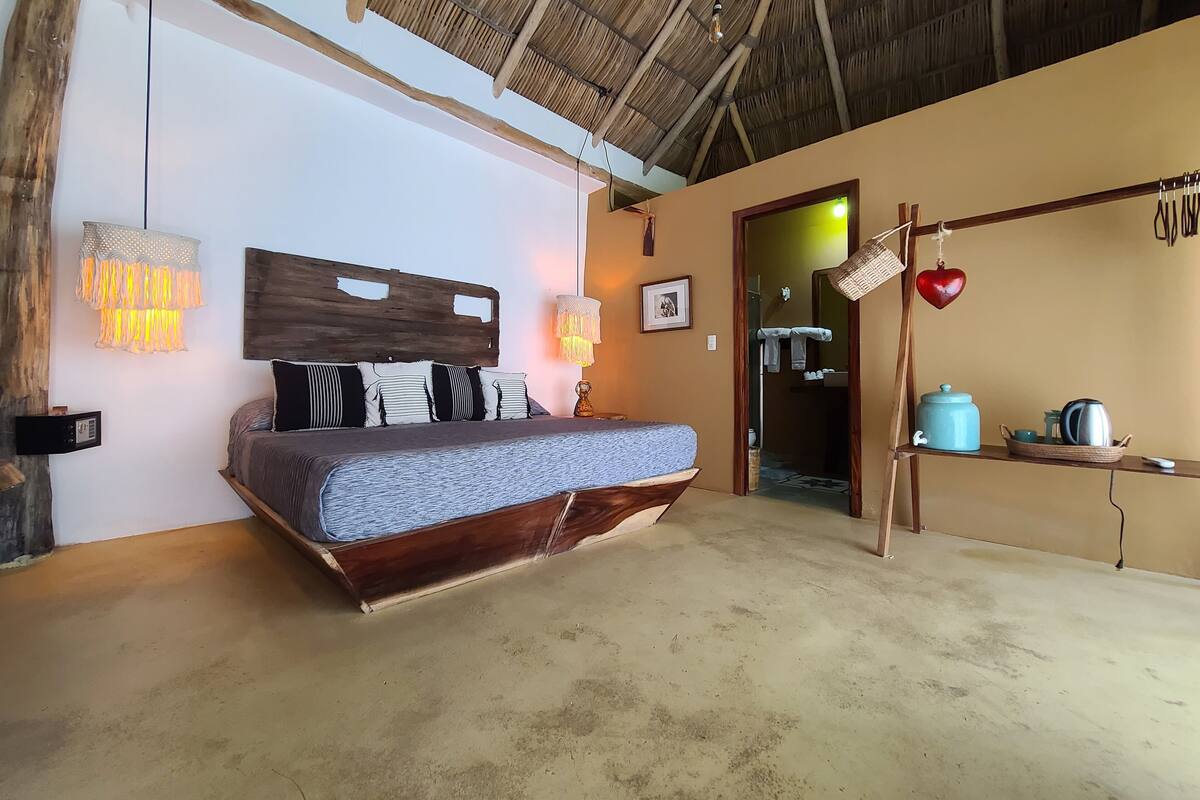 Una camera da letto con un letto, lampade sui comodini, una radio a muro e un soffitto rustico.