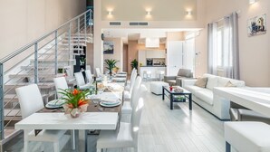 Un apartamento moderno con comedor, sala de estar, cocina y una escalera.