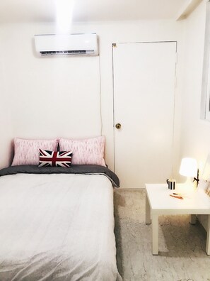Una camera da letto con un letto, un comodino con una lampada e un condizionatore d'aria a parete.