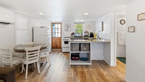 A compact kitchen with white cabinetry, a dining area with a wooden table and chairs, and a small island with a sink and microwave. - 2BR Sleeps 4 - Beach Retreat  - 100 feet to beach, Walk to Dining & Nightlife (Folly Beach)