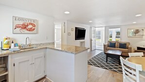 A modern kitchen with a granite countertop, white cabinetry, and a lobster-themed artwork. - 2BR Sleeps 4 - Beach Retreat  - 100 feet to beach, Walk to Dining & Nightlife (Folly Beach)