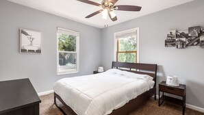 Ein Schlafzimmer mit Bett, Nachttisch, Deckenventilator und Fenster.