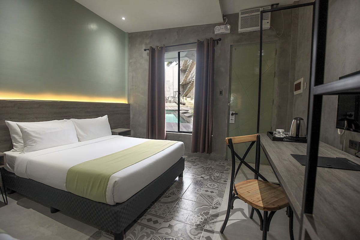 A hotel room with a bed, a desk, a chair, and a shower area.