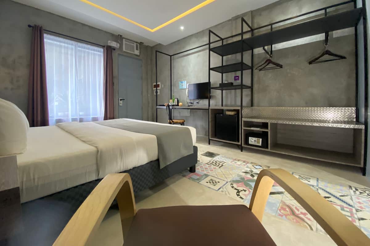 A modern hotel room with a bed, a desk, and a TV.