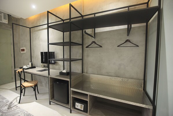 Habitación compacta y moderna con escritorio integrado, silla y perchero.