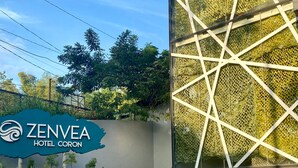 Un edificio moderno con fachada geométrica y un letrero que indica ZENVEA HOTEL CORON.