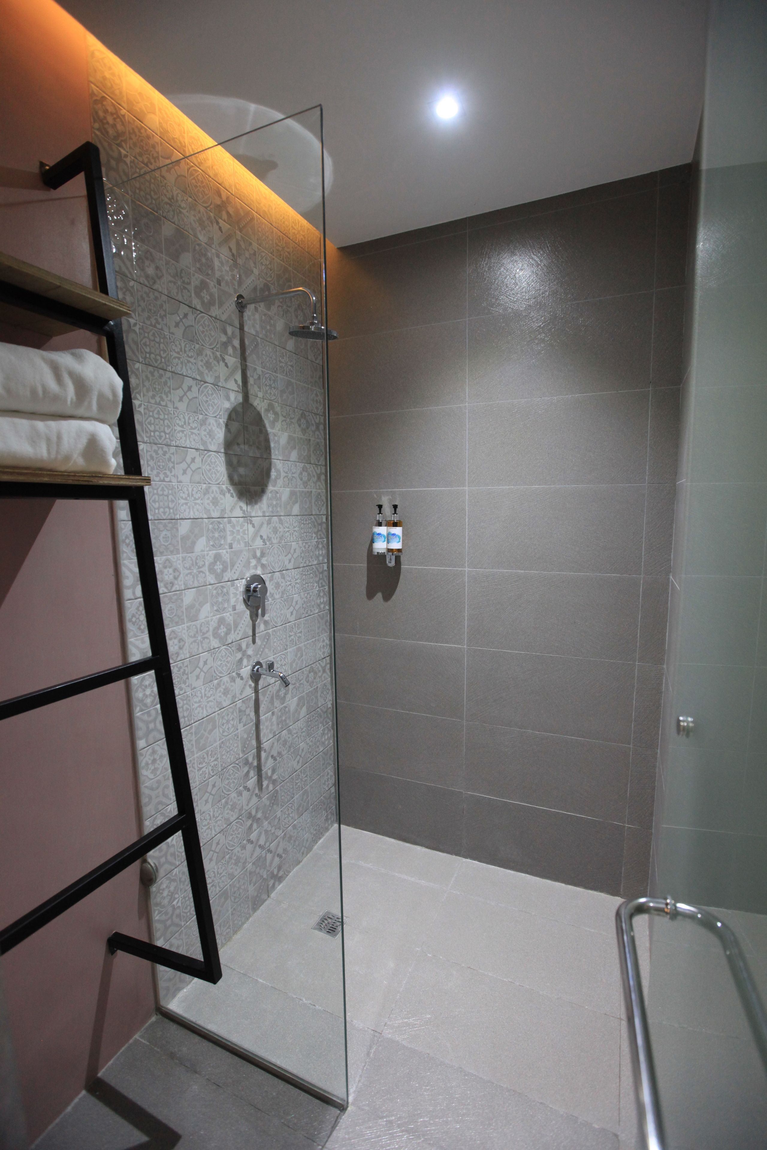 A modern shower with a glass door, a towel rack, and a handheld showerhead.