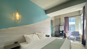 Una habitación de hotel moderna con una cama grande, un escritorio y una zona de estar.