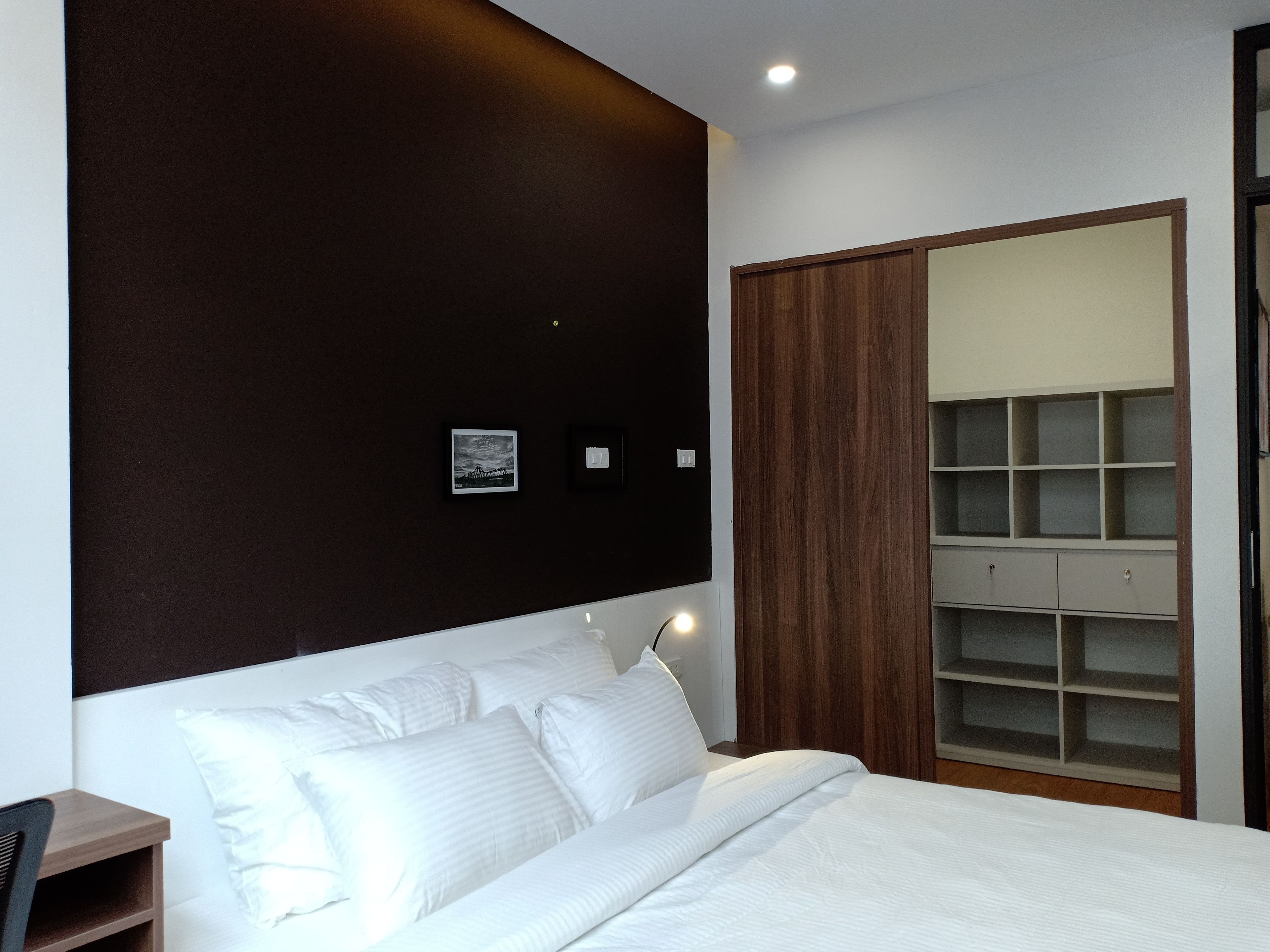 Ein Schlafzimmer mit einem Bett, einem Holzschrank und einer integrierten Regallösung.
