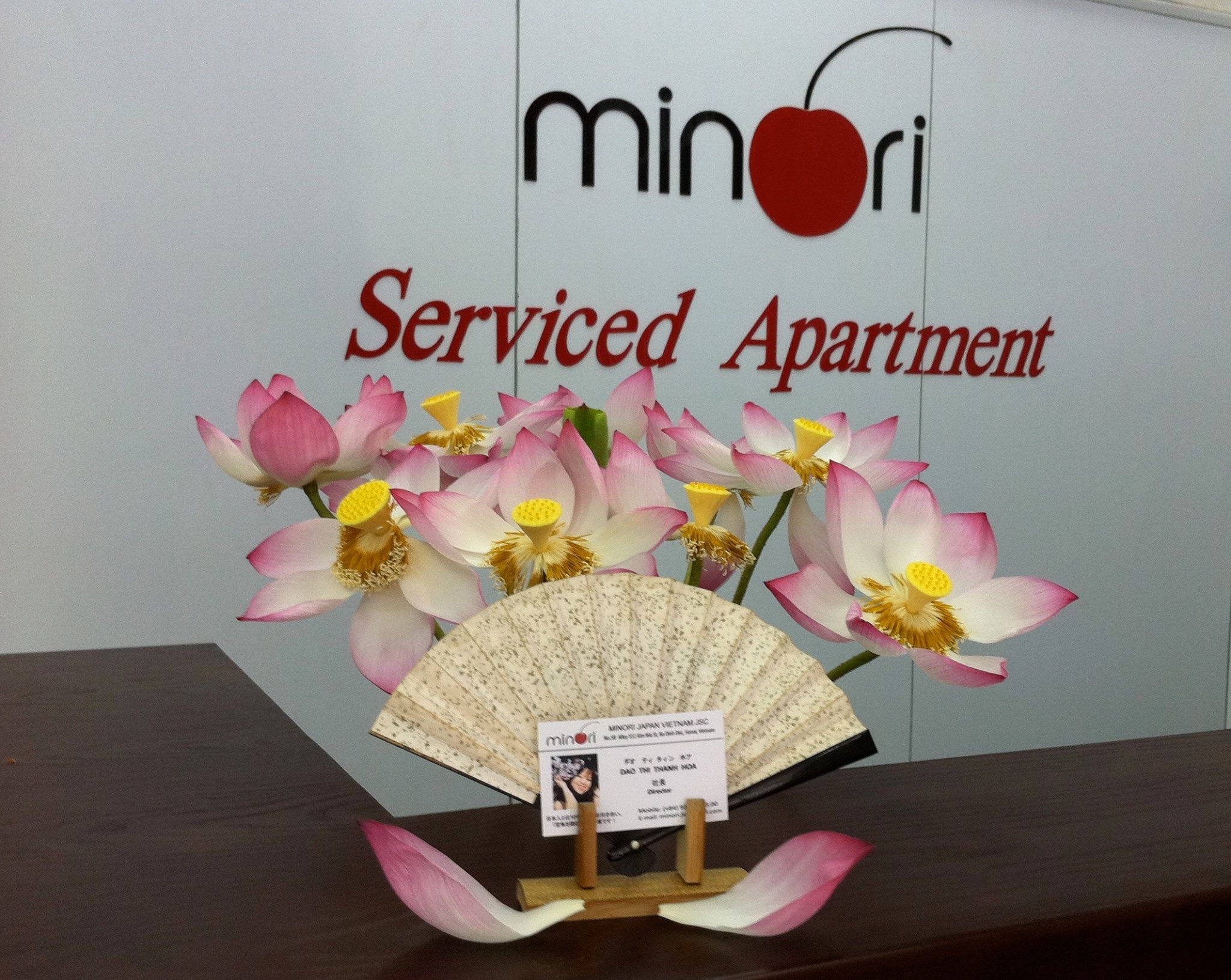 Naamplaatje voor 'Minori Serviced Apartment' met een decoratieve waaier en bloemen.