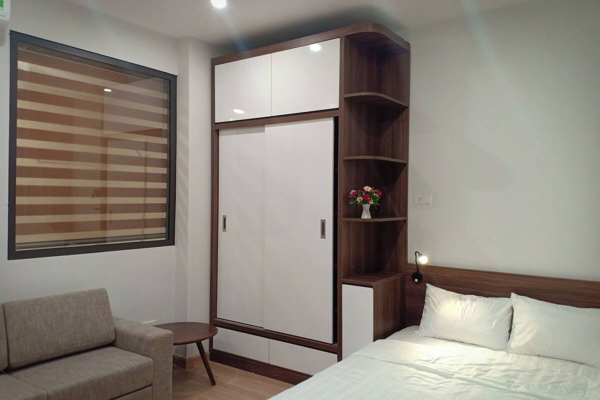 A bedroom with a bed, a sofa, a wardrobe, and a small table.