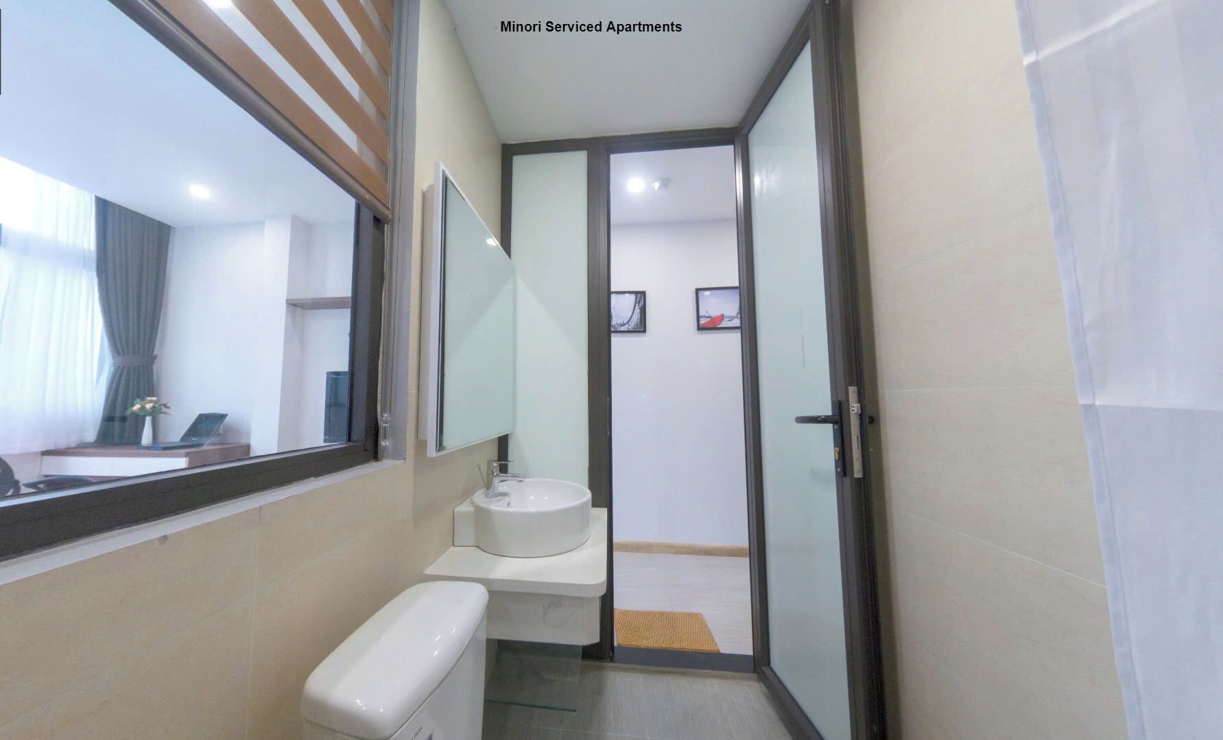 A narrow hallway leading to a bathroom with a toilet, sink, and a mirror.
