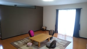 A room with a wooden table, two chairs, a small rug, and a bean bag chair. - PittINN Farm Hinata (Kuroishi)