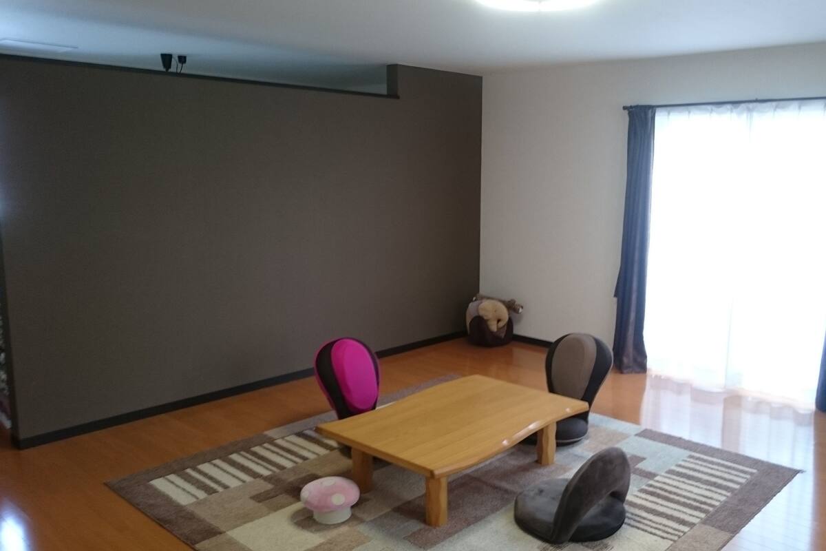 A room with a wooden table, two chairs, a small rug, and a bean bag chair.