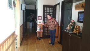 A hallway with wooden flooring, a door with a traditional lattice design, and a small table with a decorative item. - PittINN Farm Hinata (Kuroishi)