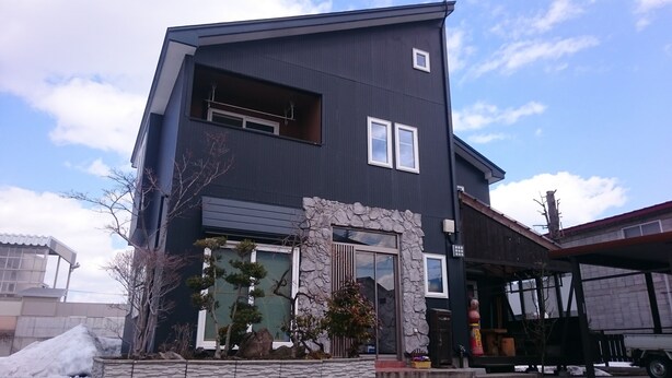 A modern two-story house with a stone facade, large windows, and a visible garage. - PittINN Farm Hinata (Kuroishi)