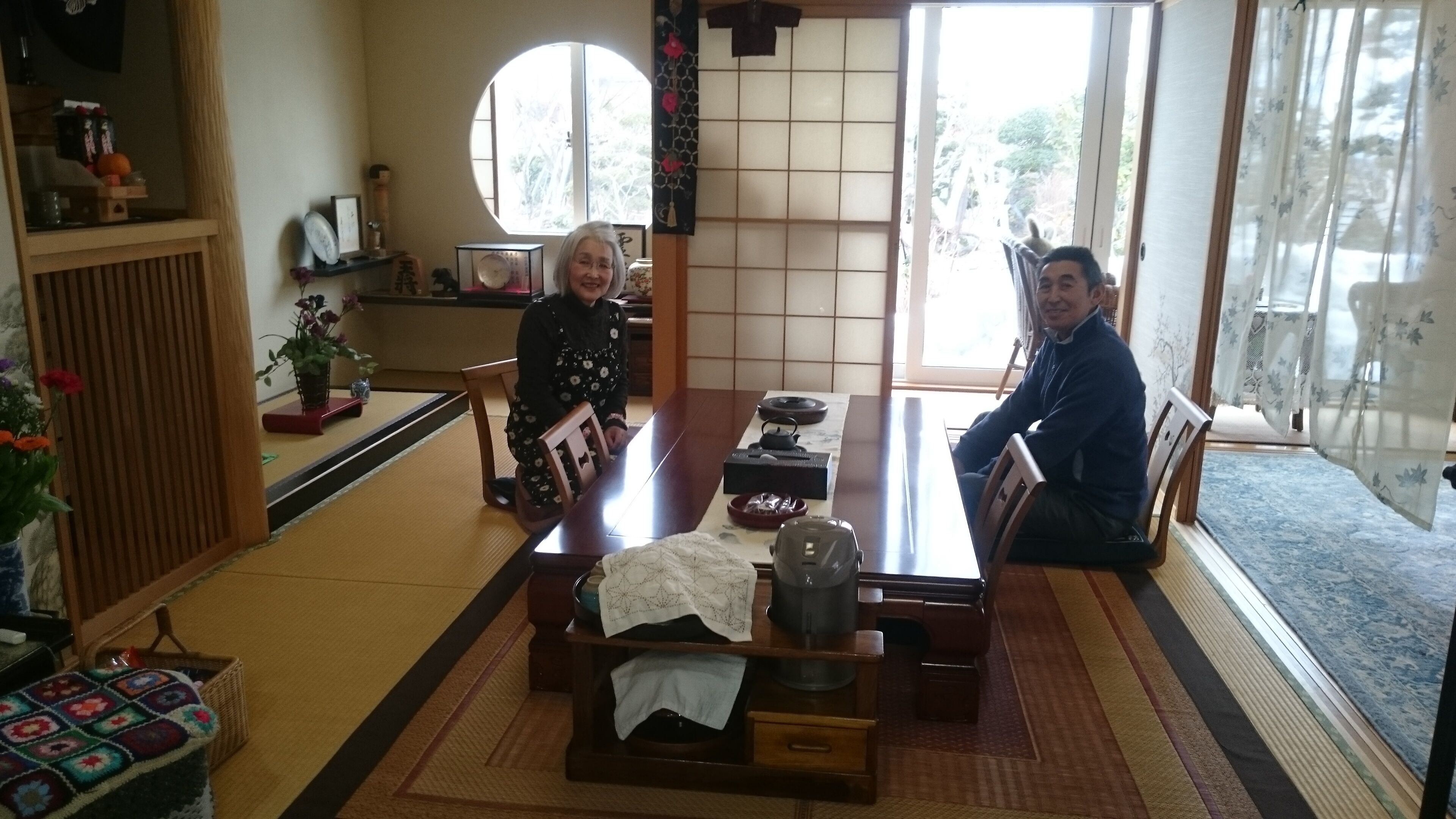 Um quarto tradicional japonês com tatames, uma mesa baixa com um conjunto de chá e portas deslizantes que dão para um jardim.