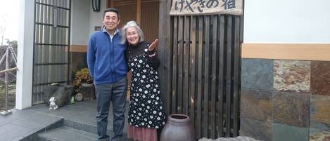 A wooden sign with Japanese characters, a traditional wooden gate, and a stone vase on the steps.